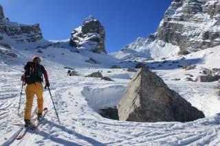 Person läuft auf Tourenski durch verschneite, felsige Berglandschaft