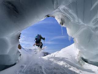 Skifahrer fährt durch Eishöhle raus in die Sonne