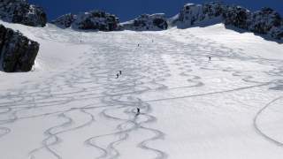Verschneiter Hang, auf dem sieben Personen mit Ski abfahren