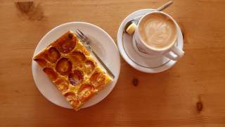 Teller mit Aprikosenkuchen, daneben steht ein Kaffee