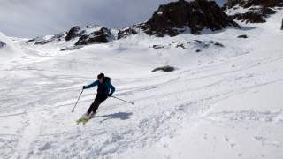 Skifahrer bei der Abfahrt, im Hintergrund dunkle Felsen