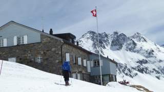 Person auf Tourenski läuft auf Berghütte zu