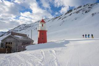 Kleiner roter Leuchtturm in verschneiter Hochgebirgslandschaft.