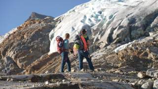 Zwei Menschen stehen in den Bergen vor Gletscher