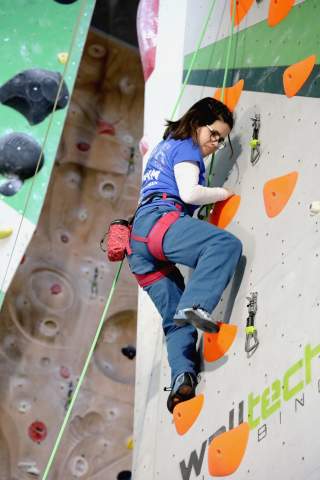 Kletterin mit Behinderung an Wand in Kletterhalle