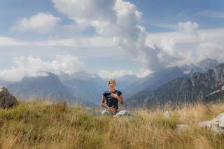 Frau macht Atemmeditation in den Bergen