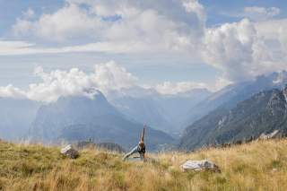 Frau macht Atemmeditation in den Bergen