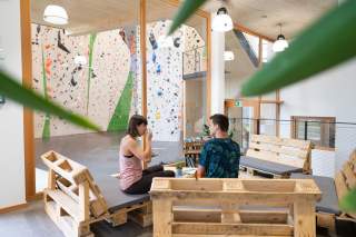 Zwei Menschen sitzen in Kletterhalle und trinken Kaffee