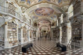 Barocke Klosterbibliothek mit Deckenmalerei und Bücherregalen.