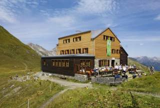 Blick auf Hütte mit Terrasse und Menschen
