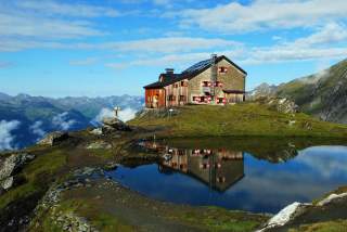 Blick auf Sudetendeutsche Hütte mit Bergsee im Vordergrund