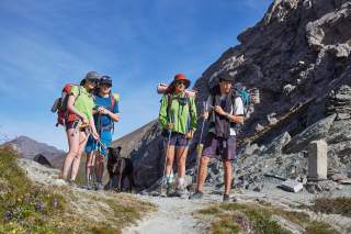 Wandergruppe mit Hund an einem Übergang am Berg