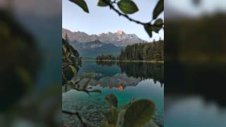 Die Zugspitze spiegelt sich im grünlich schimmernden Wasser des Eibsees.