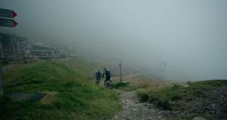 Zwei Menschen auf Mountainbikes fahren bei Nebel auf Trail