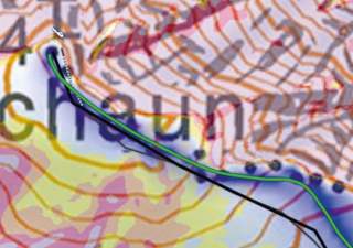 Ausschnitt einer topografischen Karte mit Höhenlinien, farblich markierten Flächen und einer grünen Linienführung entlang eines Gewässers, teilweise überlagert von Text.