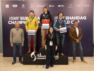 Eine Siegerehrung mit drei Athleten auf dem Siegertreppchen und drei weiteren Personen, die drum rum stehen.