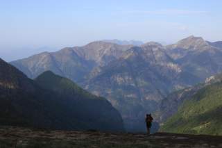 Frau wandert bergauf, im Hintergrund Ausblick auf Berggipfel