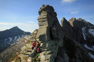 Frau sitzt vor hohen Felsen in den Bergen