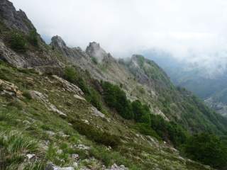 Schroffer Berghang mit Fels und Schrofen und Nebelfetzen.