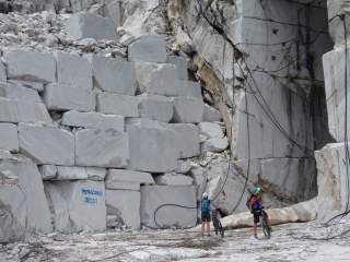 Zwei Mountainbiker stehen vor einem Marmorbruch.