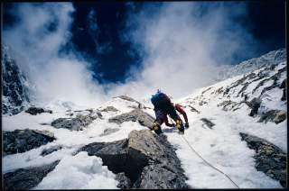 Am Seil gesicherter Bergsteiger in verschneiter Flanke