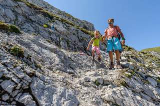 Mann hilft Kind beim Wandern in felsigem Gelände Mann hilft Kind beim Wandern in felsigem Gelände