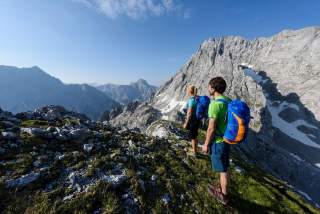 Zwei Menschen beim Wandern mit kleinen Schneefeldern im Hintergrund