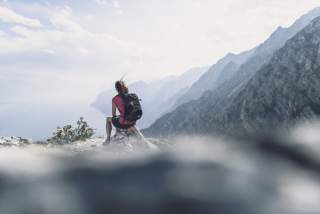 Wanderin sitzt  oberhalb eines Sees im Meraner Land