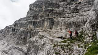 Zwei Menschen wandern auf schmalem Band im Fels