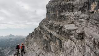 Zwei Menschen stehen in felsigem Berg und genießen die Aussicht