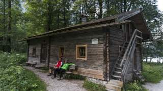 Zwei Menschen sitzen vor Holzhütte