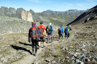 Gruppe mit Arbeitsgeräten läuft Bergweg runter