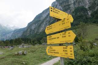 Im Gebirge: viele Wegweiser mit roter, blauer und schwarzer Markierung.