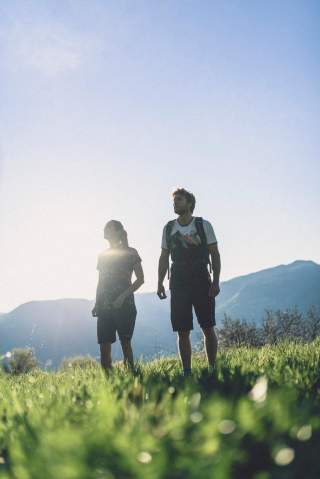 Zwei Menschen wandern auf Wiese in der Sonne