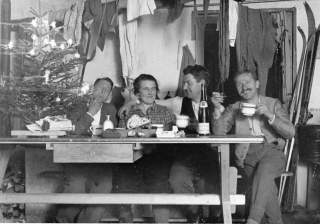Historisches Bild von vier Menschen, die in Almhütte Weihnachten feiern
