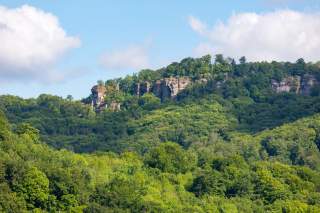 Das Foto zeigt den oberen Teil des Hohensteins im Weserbergland. Die aus dem dichten Laubwald ragenden Felsen befinden sich im Landkreis Hameln-Pyrmont und gelten als beliebtes Klettergebiet.