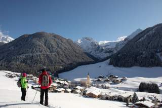 Zwei Menschen wandern im Winter bei Sonnenschein in den Bergen