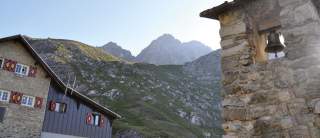 Berghütte mit Glockenturm und Blick in die Berge