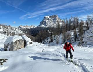 Person geht mit Tourenski durch verschneite Winterlandschaft