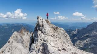 Bergsteigerin genießt die Aussicht auf dem Grat, von dem man zum Höllentalklettersteig abseilt.