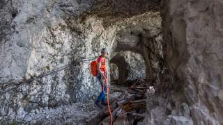 Bergsteigerin läuft durch den Stollen des Tunnelbauersteig der Route Eisenzeit
