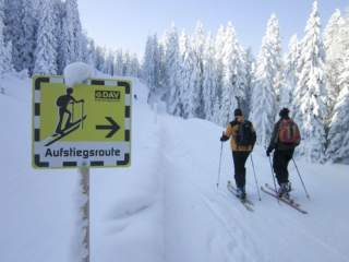 Zwei Menschen gehen Skitour auf gekennzeichneter Aufstiegsroute