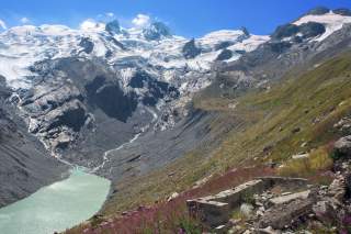 Blick auf den weit zurückgezogenen Roseggletscher im Jahr 2015, im Tal sammelt sich das milchig-türkisfarbene Schmelzwasser, im Vordergrund Grundmauern einer ehemaligen Hütte.