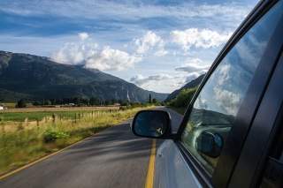 Auto auf Landstraße mit Blick Richtung Berge