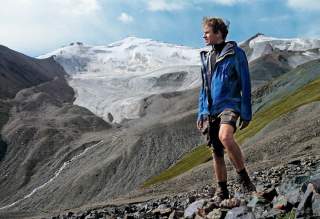 Ein Mann in blauer Windjacke und kurzer Hose, Autor Martin Roos, vor dem Blockgletscher TienShan.