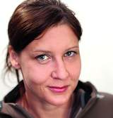 Porträt einer Frau mit braunen Haaren, die lächelnd in die Kamera blickt.