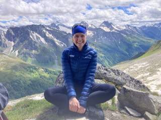 Johanna Felber sitzt im Schneidersitz vor einem Hochgebirgspanorama Johanna Felber sitzt im Schneidersitz vor einem Hochgebirgspanorama