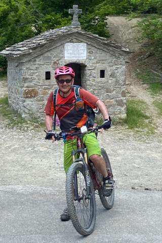 Der Autor und MTB-Guide Traian Grigorian auf dem Mountainbike vor einer mediterranen Kapelle.