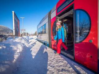 Frau steigt an winterlichem Bahnhof aus Zug aus