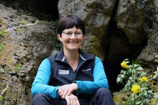 Barbara Eichler sitzt vor Felsvorsprung und lächelt.